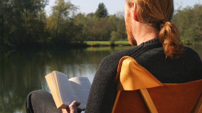 Modell Mit Strickpullover Im Kampierstuhl Mit Buch Von Hinten