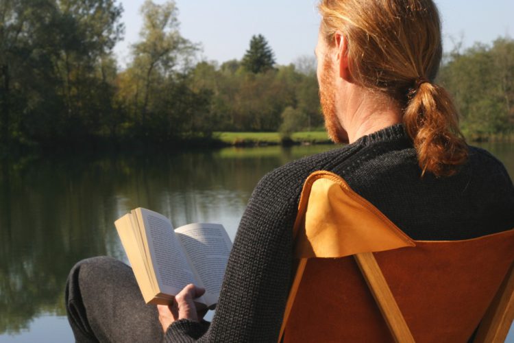 Modell Mit Strickpullover Im Kampierstuhl Mit Buch Von Hinten